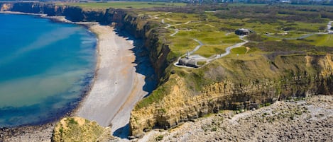 A coastal landscape with a beach, cliffs, and a clear sky.