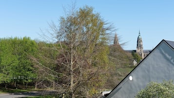 A residential area with a curved road, a large tree, and a church spire in the background.