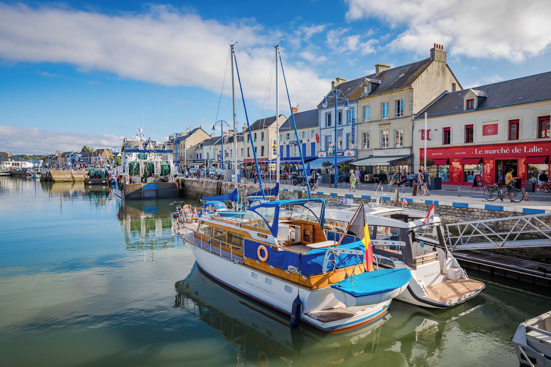 A harbor with boats docked, a waterfront promenade, and buildings with commercial establishments.
