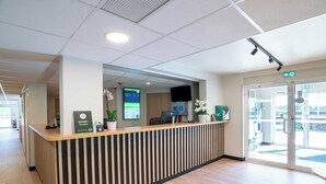 En receptionsdisk med en digital skärm, en krukväxt och en skylt med texten ”Respirateur BreatheWell”.