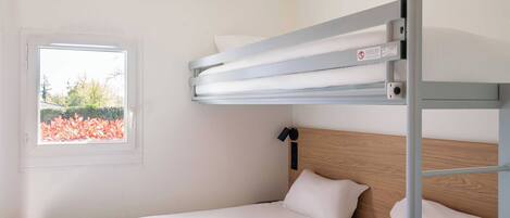 Una cama litera con ventana, ropa de cama blanca y cabecero de madera.