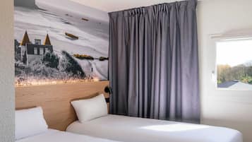 Habitación de hotel con dos camas, cabecera, un ventanal grande y un mural en la pared.