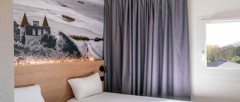 A hotel room with two beds, a headboard, a large window, and a mural on the wall.