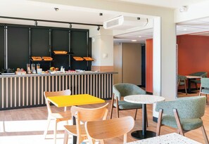 Um café moderno com balcão, mesas e vista para o espaço adjacente.