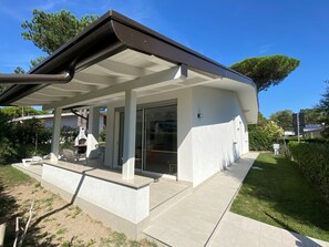 Ein modernes Haus mit überdachter Terrasse, Garage und gepflegtem Rasen.