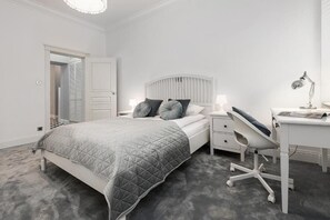 A bedroom with a bed, bedside table, desk, chair, and a door leading to another room. - ShortStayPoland Ludna B195  (Warszawa)