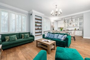 A modern living room with a green sofa, a wooden coffee table, and a kitchen in the background. - ShortStayPoland Ludna B195  (Warszawa)