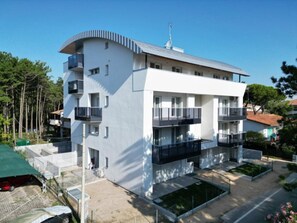 Ein modernes, mehrstöckiges Gebäude mit Balkonen, einer flachen Dachterrasse und einem kleinen Innenhof.