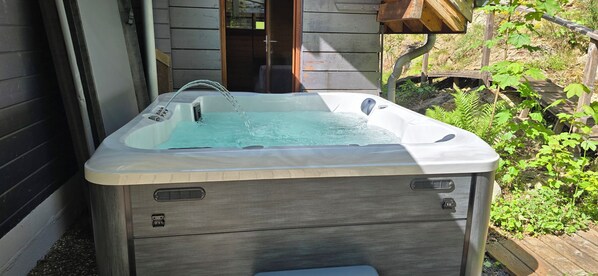 Een hottub met een houten buitenkant, een ingebouwde zitplaats en een waterspuit.