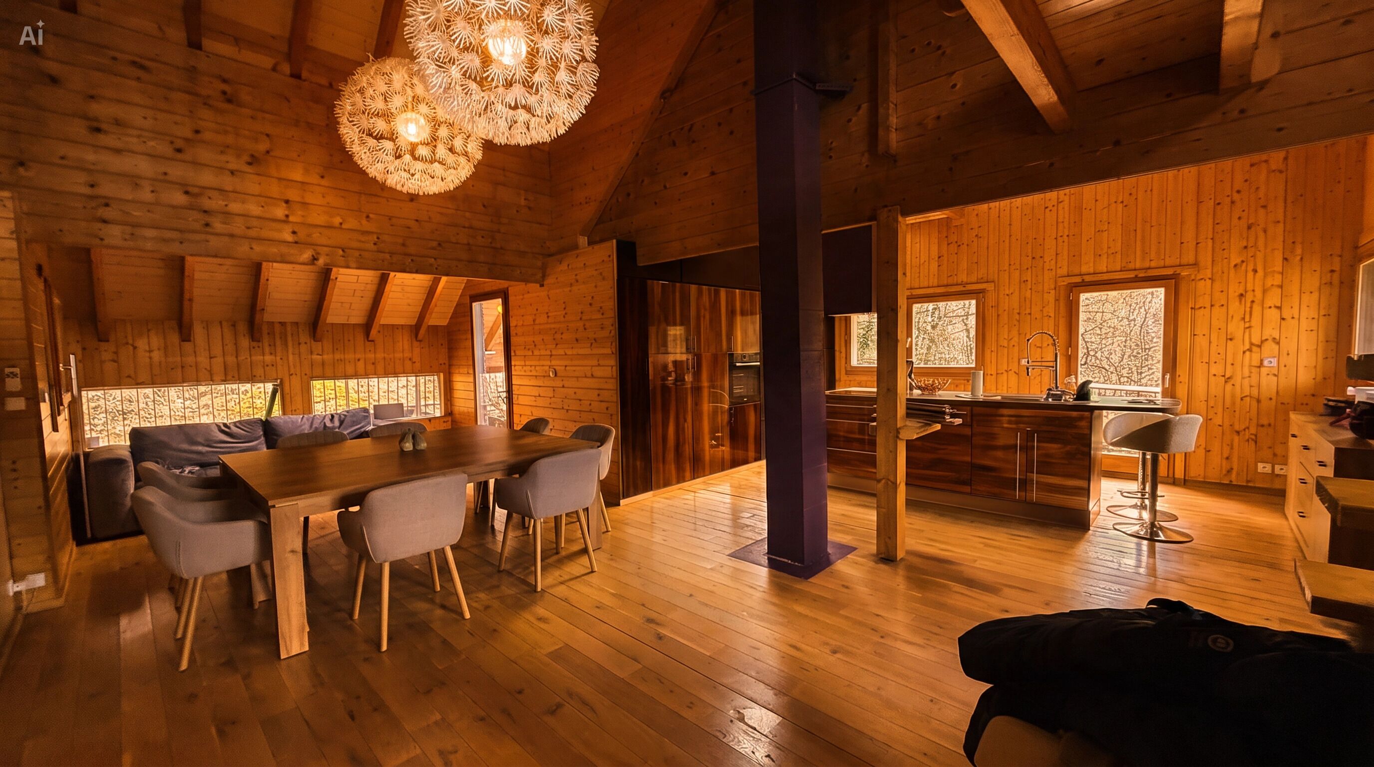 Interno di una baita in legno con zona pranzo, cucina e ampie finestre.