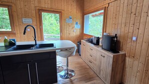 Une cuisine de style rustique, avec des éléments en bois, comprenant un évier, un tabouret de bar et une machine à café.