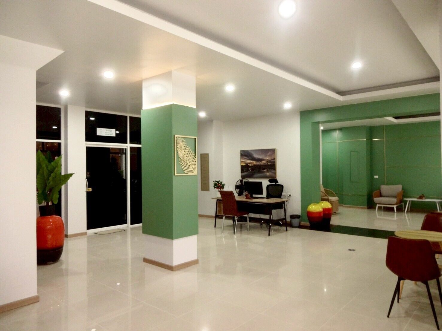A spacious living area with a dining table, chairs, and a green accent wall.