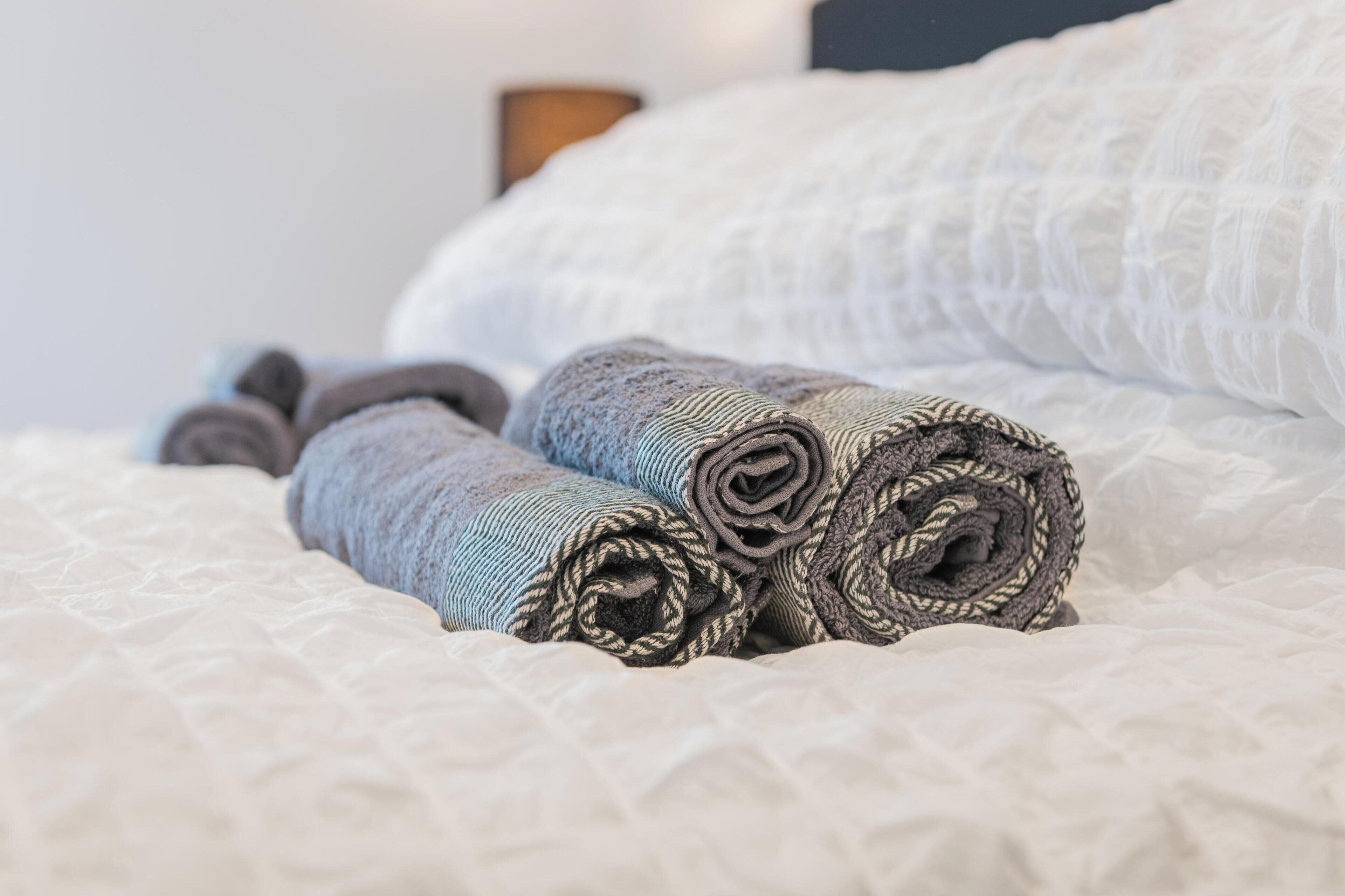 Ein Bett mit aufgerollten Handtüchern und einer weißen gesteppten Decke.
