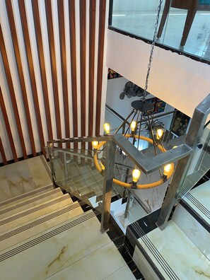 En modern trappa med glasräcken, en hängande lampa och utsikt över interiören.