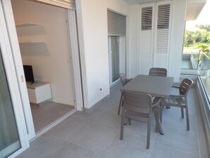 Ein Balkon mit Tisch und Stühlen, eine Schiebetür und ein Fenster mit Jalousien.