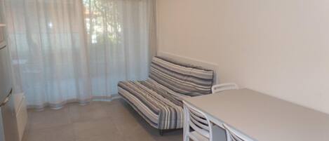 A room with a sofa, a table, and chairs.