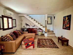 Ein Wohnzimmer mit einer Couch, einem Teppich mit Muster, einer Treppe und einem Bild an der Wand.