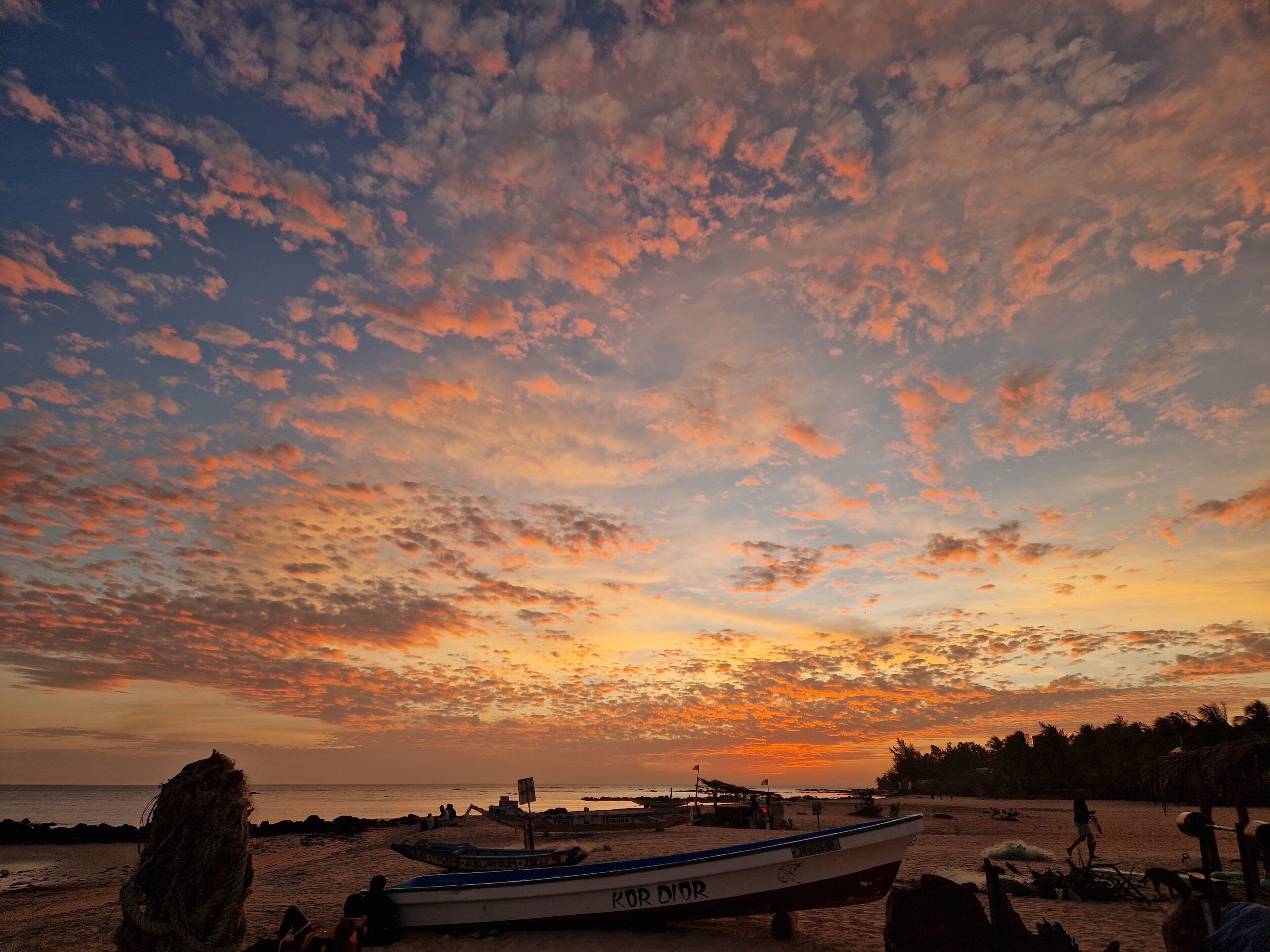 Cena de praia com barcos e céu claro.