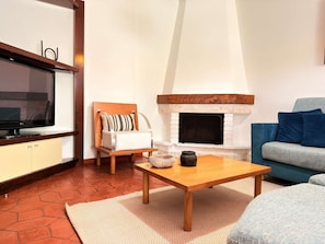 Ein Wohnzimmer mit Fernseher, Kamin, Sofa und Couchtisch.