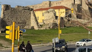 Un bâtiment historique en pierre, avec un toit rouge, un feu de signalisation et un panneau de signalisation.