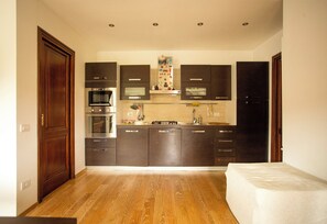 A compact kitchen with dark cabinets, a microwave, oven, and a small countertop area. - Relax Pescasseroli For Ever (Abruzzo)