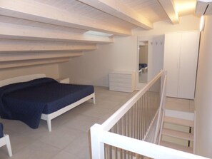 Ein Schlafzimmer mit einem Bett, einem Schminktisch, einem Kleiderschrank und einer Treppe.