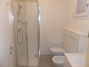 Ein Badezimmer mit Duschkabine, Toilette und Badewanne.