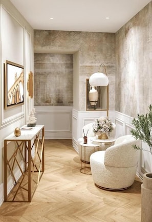 A room with a wooden floor, a round table with a white chair, a white lamp, and a framed picture on the wall. - Agava Design Residence (Split)