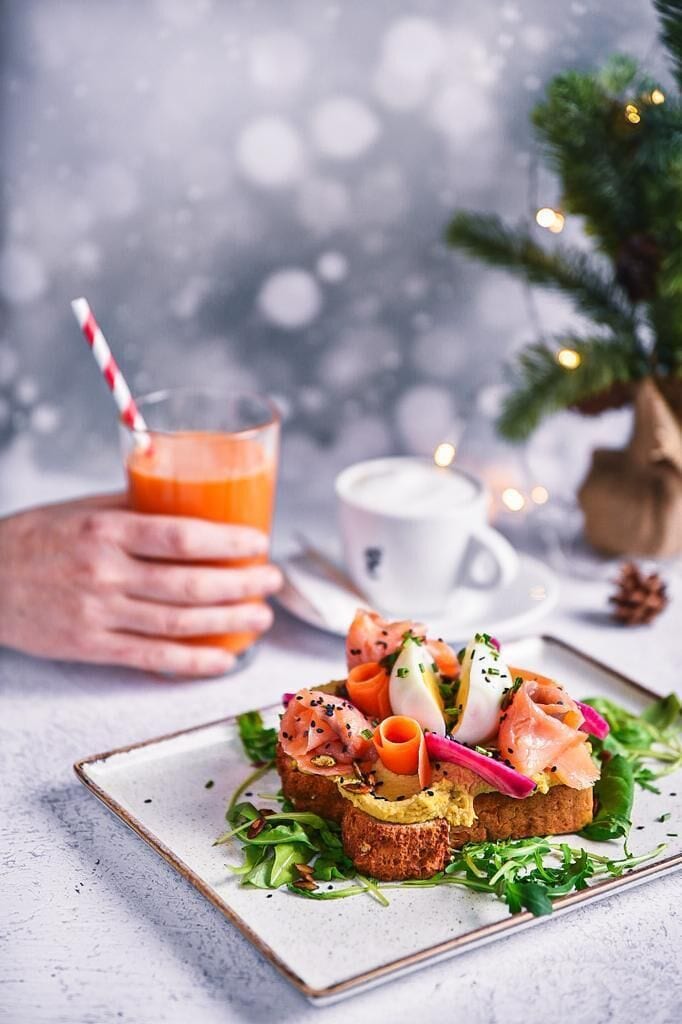 Un plato con un sándwich, un vaso de jugo de naranja y una taza de café sobre una mesa.
