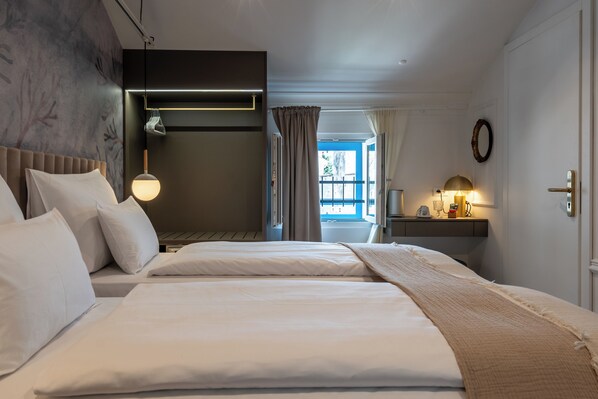 Habitación de hotel con cama, mesita de noche, lámpara y vistas al exterior.