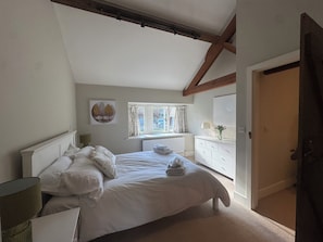Une chambre à coucher avec un lit, une fenêtre, une commode et un tableau accroché au mur.