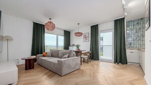A modern living room with a sofa, a dining table, and a small side table. - ShortStayPoland Szwedzka B196 (Warszawa)