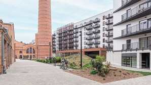 A tall brick chimney, modern apartment buildings, and a paved walkway. - ShortStayPoland Szwedzka B196 (Warszawa)