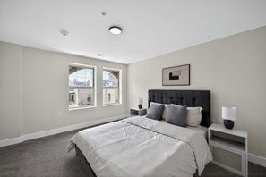A bedroom with a large bed, two bedside tables, a headboard, a window, and a ceiling light. - Bright and stylish fully furnished unit (Reading)