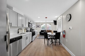 A modern kitchen with stainless steel appliances, a dining area with a table and chairs, and a view of the outside through a window. - Bright and stylish fully furnished unit (Reading)