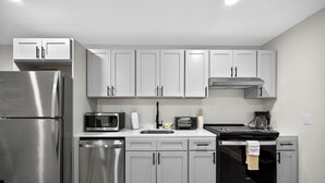 Una cocina con electrodomésticos de acero inoxidable, armarios blancos y un horno negro.
