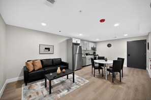 Eine moderne Wohnung mit Wohnzimmer, Essbereich, Küchenzeile und einem separaten Schlafzimmer.