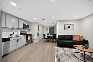 Eine moderne Küche mit weißen Schränken, einer Mikrowelle und einem Essbereich mit einer schwarzen Ledersofa und einem Couchtisch.