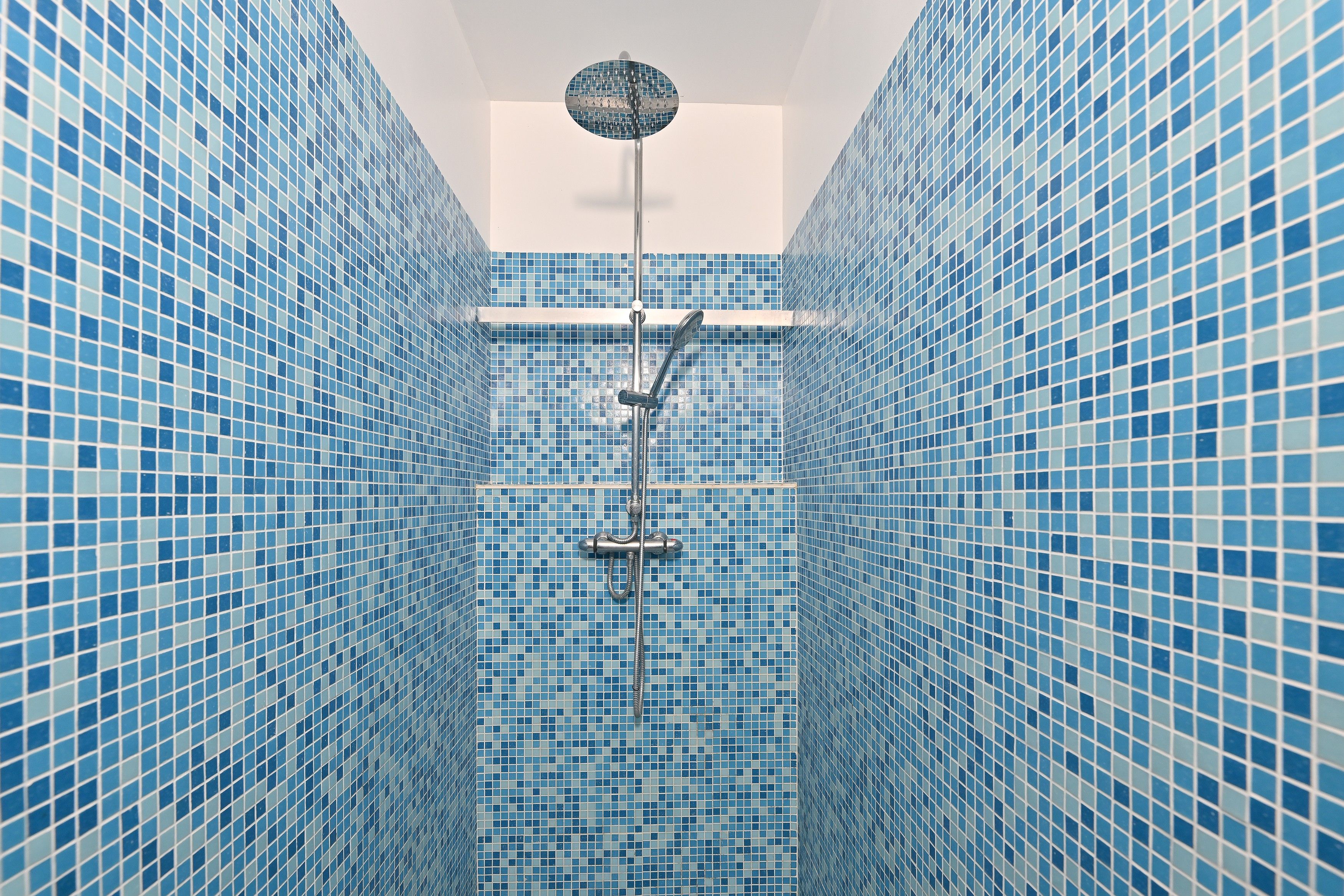Ein Badezimmer mit blauen Mosaikfliesen und einer Duschkabine.