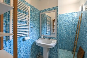 A bathroom with a white sink, a mirror, and blue mosaic tiles on the walls.