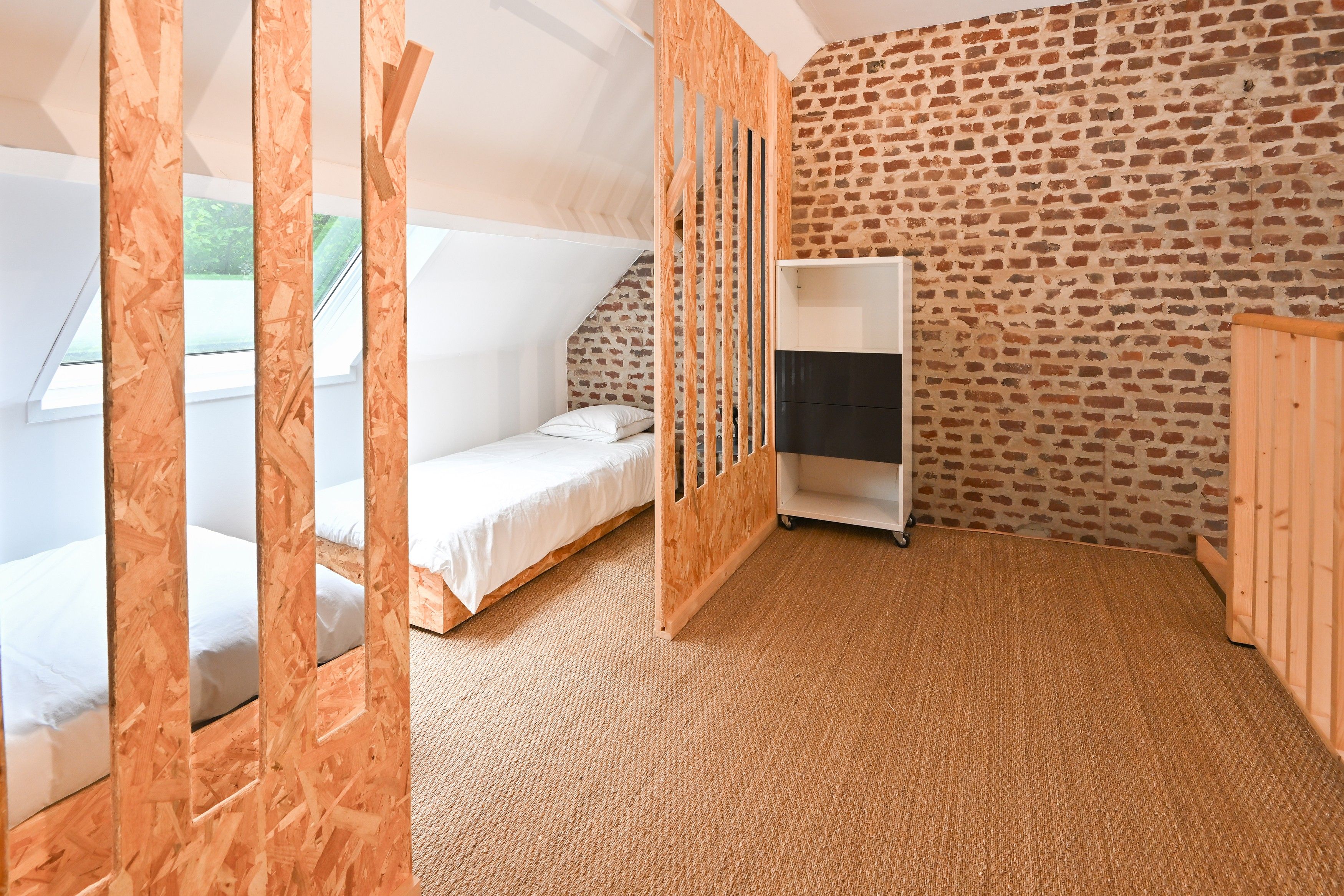A room with a loft bed, a small desk, and a brick-patterned wall.