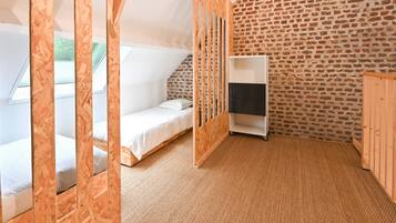 A room with a loft bed, a small desk, and a brick-patterned wall.