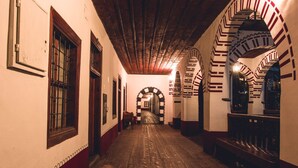 A corridor with wooden flooring, arched doorways, and a bench.
