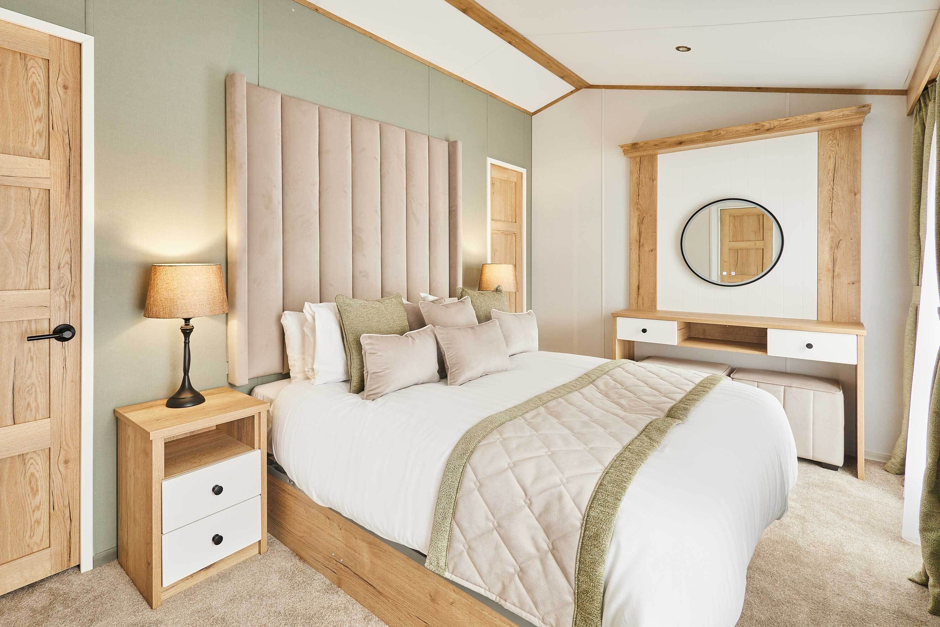 Une chambre à coucher comprenant un lit, des tables de chevet, un bureau, un miroir et une armoire.