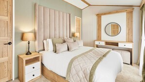 Ein Schlafzimmer mit Bett, Nachttischen, Schreibtisch, Spiegel und Kleiderschrank.