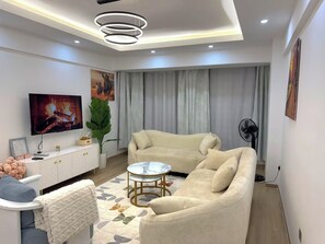 Ein modernes Wohnzimmer mit einer Couch, einem Couchtisch, einem Fernseher und einer Zierpflanze.