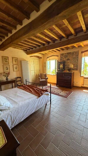 Ein Schlafzimmer mit Bett, Stuhl, Kommode und einer Steinwand.