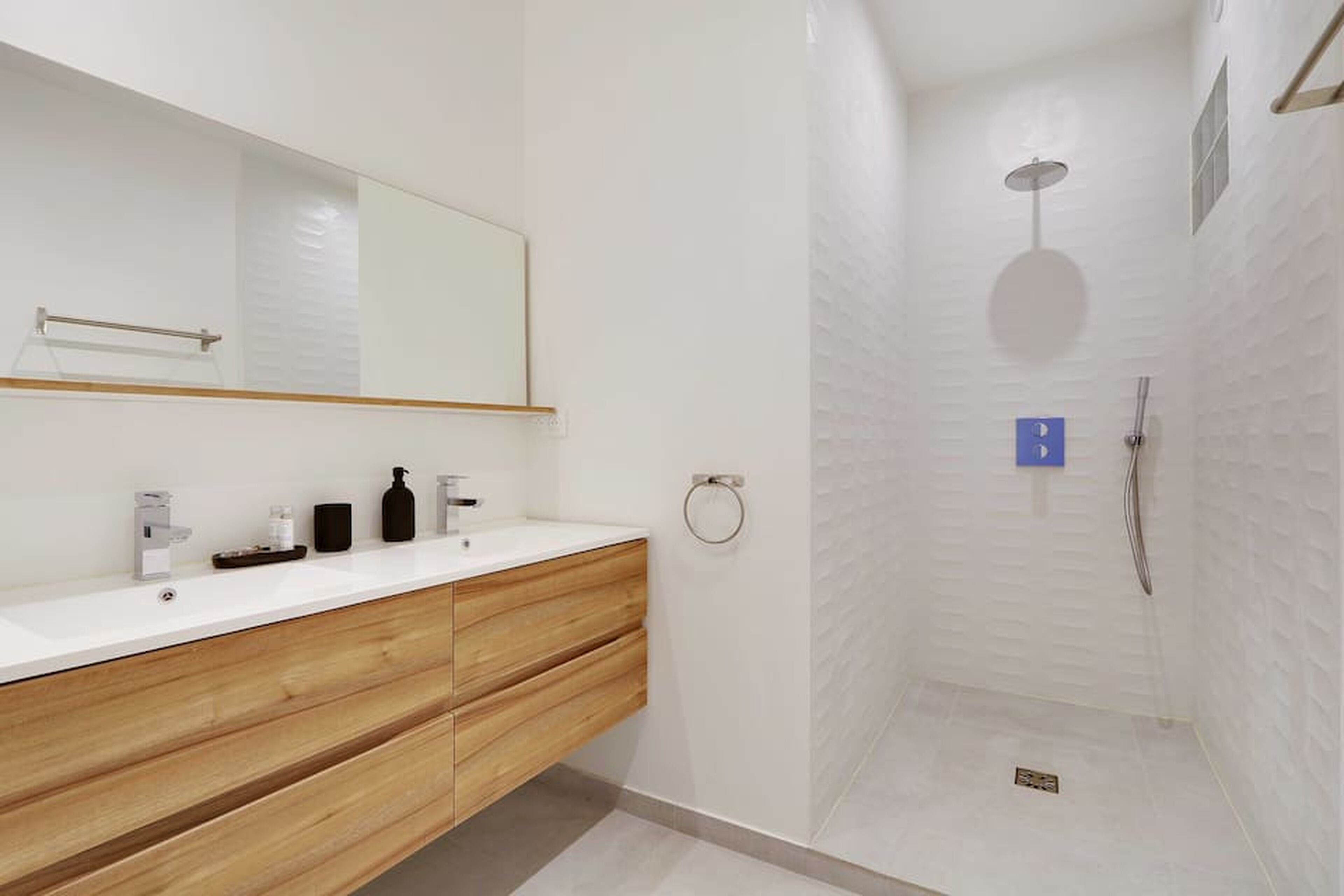Un bagno moderno con un mobile bagno in legno, uno specchio grande e una doccia a ingresso comodo.