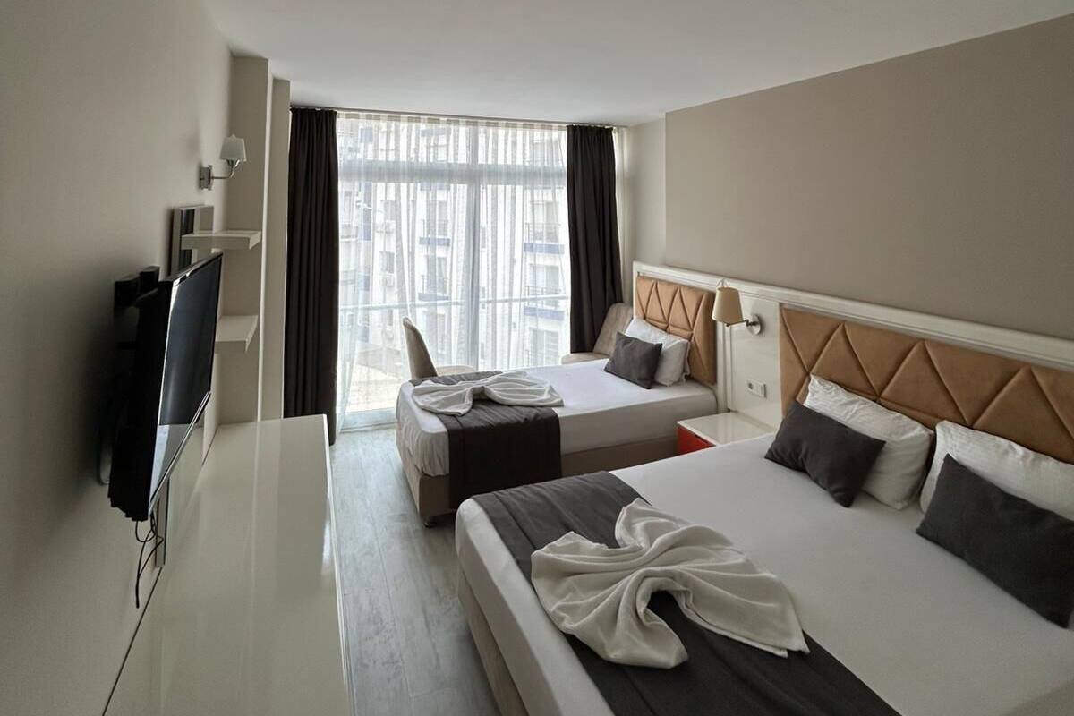 A hotel room with two beds, a desk, and a TV.