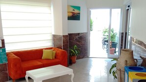 Eine moderne Lobby mit einem roten Sofa, einem weißen Couchtisch, Topfpflanzen und einem gefliesten Boden.